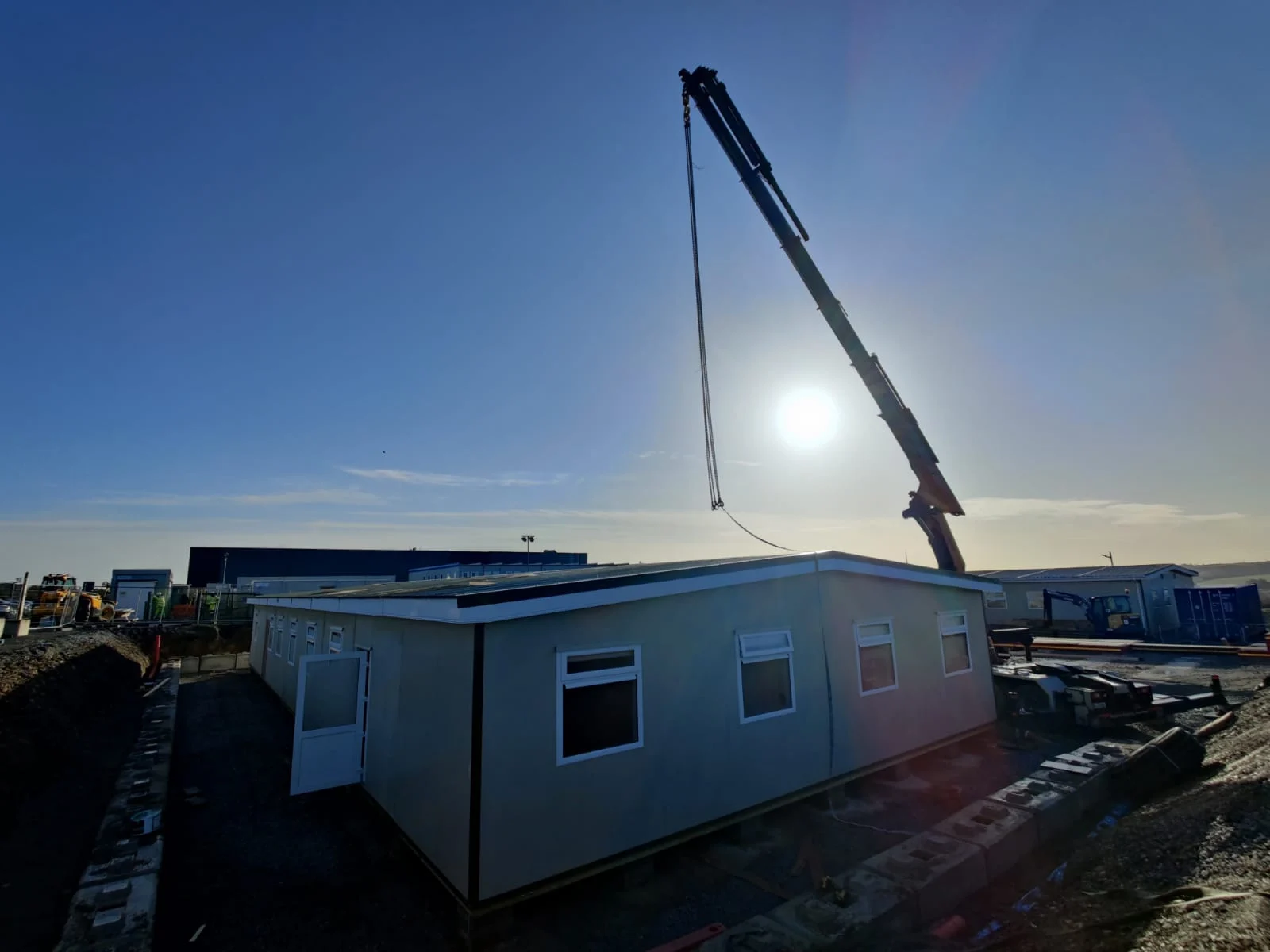 Hayes crane truck lifting a modular building into position on site at dawn
